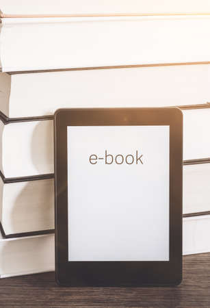 e-book reader on a stack of books on rustic wooden table conceptの写真素材