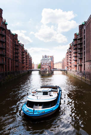 boat on a channel in the old warehouse district Speicherstadt in Hamburg, Germany under blue skyのeditorial素材