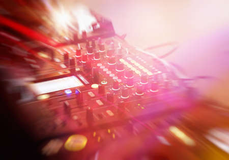 DJ mixer console in nightclub with motion blur and light beams at party eventの写真素材