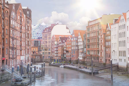 historic buildings on both sides of Nikolaifleet channel in Hamburg, Germany with Elbphilharmonie concert hall in background under blue summer skyの写真素材