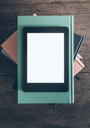 e-reader on stack of books on rustic wooden deskの写真素材
