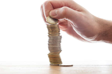 hand piling up stack of euro coins with bright background savings conceptの写真素材