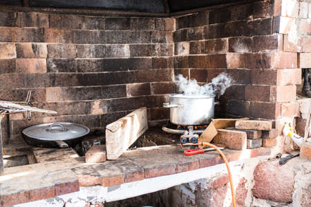 outdoor cooking area made of bricks with steaming pot on gas flameの写真素材