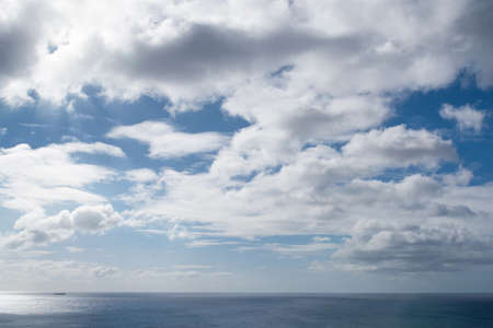 beautiful cloudscape against blue sunny sky above oceanの写真素材