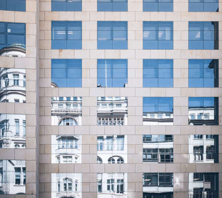 historic building mirrored in glass facade of modern office building old and new contrasting conceptの写真素材
