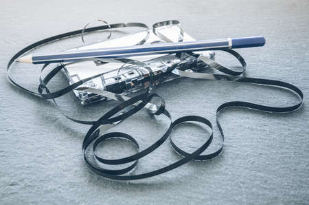 close-up of tangled-up audio tape with pencil on top on grey stone backgroundの写真素材