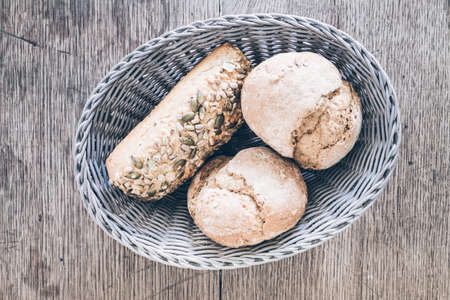 top view of basket with German style bread rolls on old rustic wooden tableの写真素材