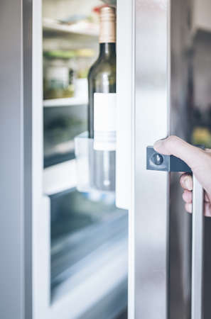 hand of a man opening refrigerator door in kitchenの写真素材