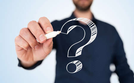 businessman in blue shirt with pen drawing question markの写真素材