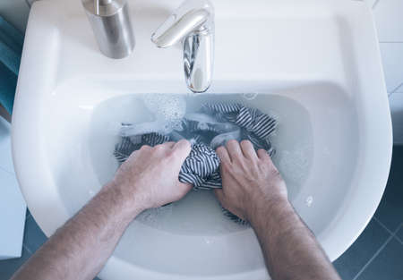 Top view of person hand washing striped shirt in sinkの写真素材