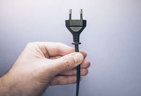 close-up of male hand holding electric plugの写真素材
