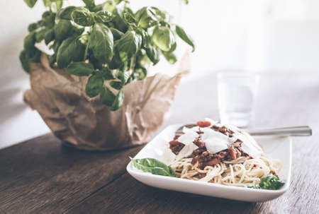 close-up shot of of pasta with Bolognese sauce, basil and grated Parmesan cheese on rustic wooden tableの写真素材