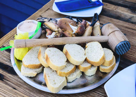 plate with boiled legs and claws of brown crab with bread and dip on rustic wooden table
