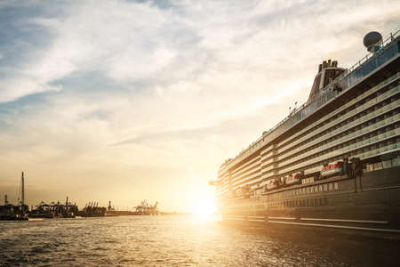low angel view of large cruise ship leaving harbor during sunset