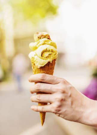 female hand holding ice cream cone against blurred background