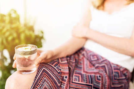 close-up of blond woman relaxing on patio holding iced drink