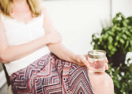 close-up of blond woman relaxing on patio holding iced drinkの写真素材