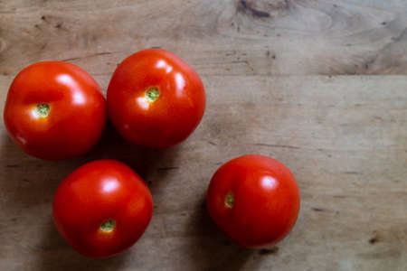close-up top view shot of ripe red tomatoes on wooden cutting board