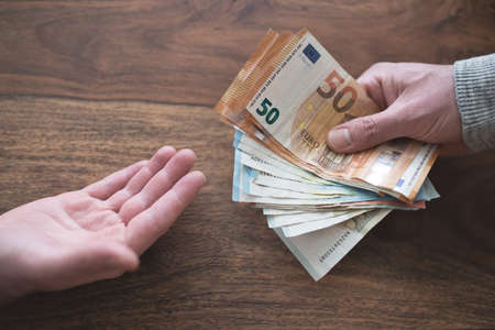 hand of one person handing over cash to another
