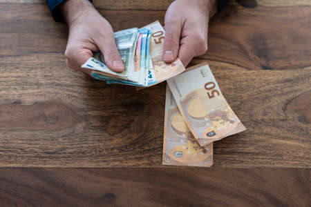 top view close-up of man counting money at desk