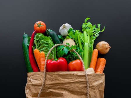 fresh organic vegetables in brown paper bag against dark table backgroundの写真素材