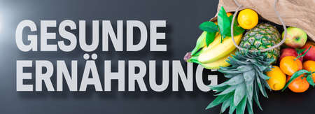 words GESUNDE ERNÃHRUNG, German for healthy eating or healthy nutrition, with fresh fruits in paper bagの写真素材