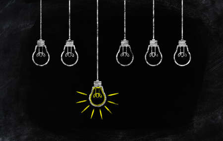 chalk drawing of one standing out glowing light bulb besides others not glowingの写真素材