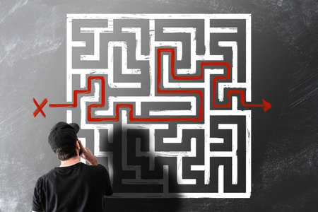 rear view of man looking at chalk drawing of maze labyrinth on blackboard