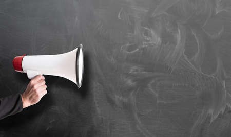 hand holding red and white megaphone against chalkboard template