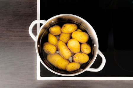 directly above shot of cooking pot with potatoes and water on stoveの写真素材