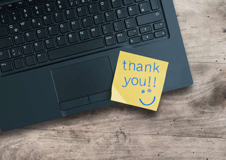 top view of words thank you written on sticky note on laptop computerの写真素材