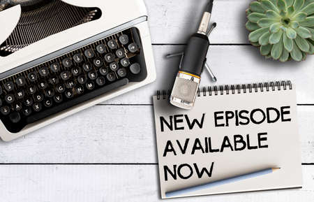 podcast concept, top view of microphone on desk with old typewriter and notepad with text NEW...