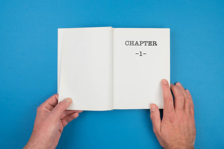 top view of person fiipping open a book with text CHAPTER 1 on first page against blue backgroundの写真素材