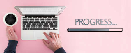 work progress concept, above view of person working on laptop computer and progress bar on pink colored table backgroundの写真素材