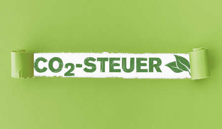 torn paper with text CO2-Steuer, German for Carbon Tax, and green leaves in openingの写真素材