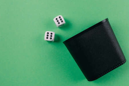 top view of dice shaker and dices on green gambling table backgroundの写真素材