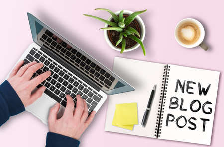 blogging and content creation concept, text NEW BLOG POST on notepad next to person working on laptop computerの写真素材