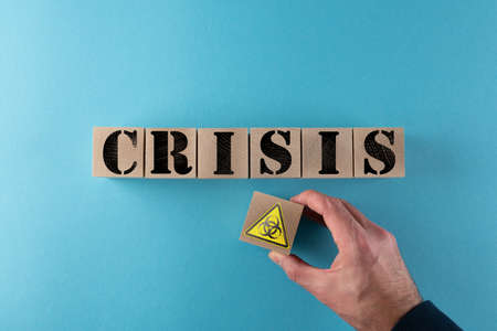 top view of word CRISIS and biohazard warning sign on wood cubes, biological threat and virus crisis...