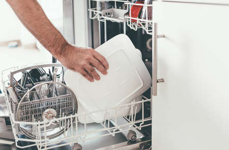 close-up of person emptying or loading dishwasher in kitchenの写真素材