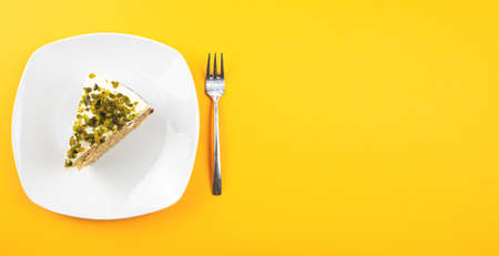 top view of piece of carrot pistachio cake on plate against orange background