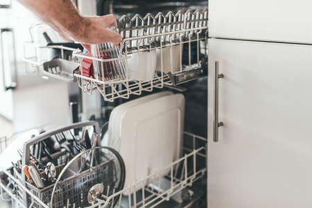 close-up of man loading or emptying dishwasher in kitchenの写真素材