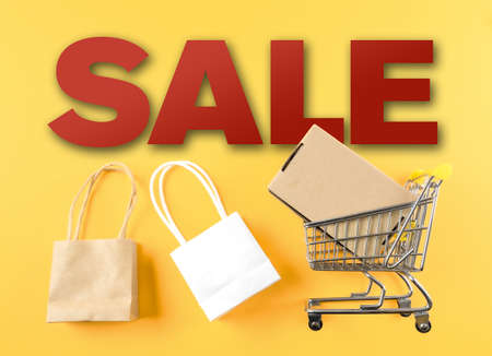 retail sale marketing concept with word SALE and shopping cart and bags against yellow backgroundの写真素材