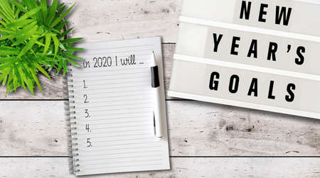 new years goals or resolutions concept with top view of lightbox and notepad on wooden tableの写真素材