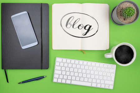 blogging concept, top view of word BLOG on note pad on desk with computer keyboard, coffe mug and potted plantの写真素材