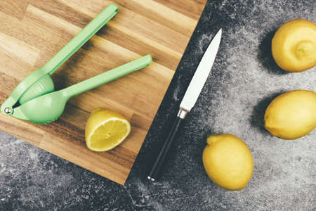 directly above view of ripe organic lemons on kitchen counter with wooden cutting board, knife and citrus juicerの写真素材