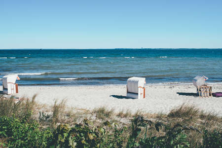 canopied beach chairs on sand beach against baltic sea and clear blue skyの写真素材