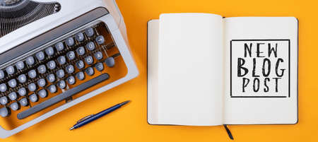 above view of old typewriter and diary with text NEW BLOG POST on orange colored desk, blogging conceptの写真素材