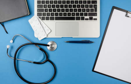 top view of desk of doctor or physician with stethoscope, laptop computer, book and clipboard with...