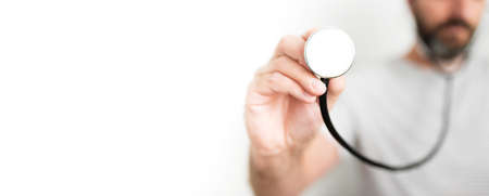 front view of hand of male physician holding stethoscope against white backgroundの写真素材