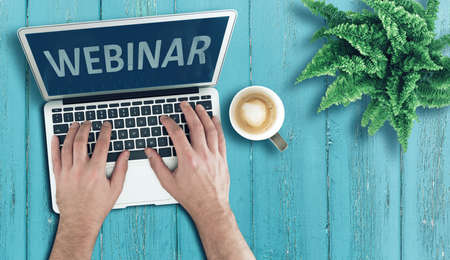 above view of person using laptop computer on wooden table to participate in webinar, online...